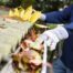 Man wearing work gloves clearing out multicolored leaves from a home gutter