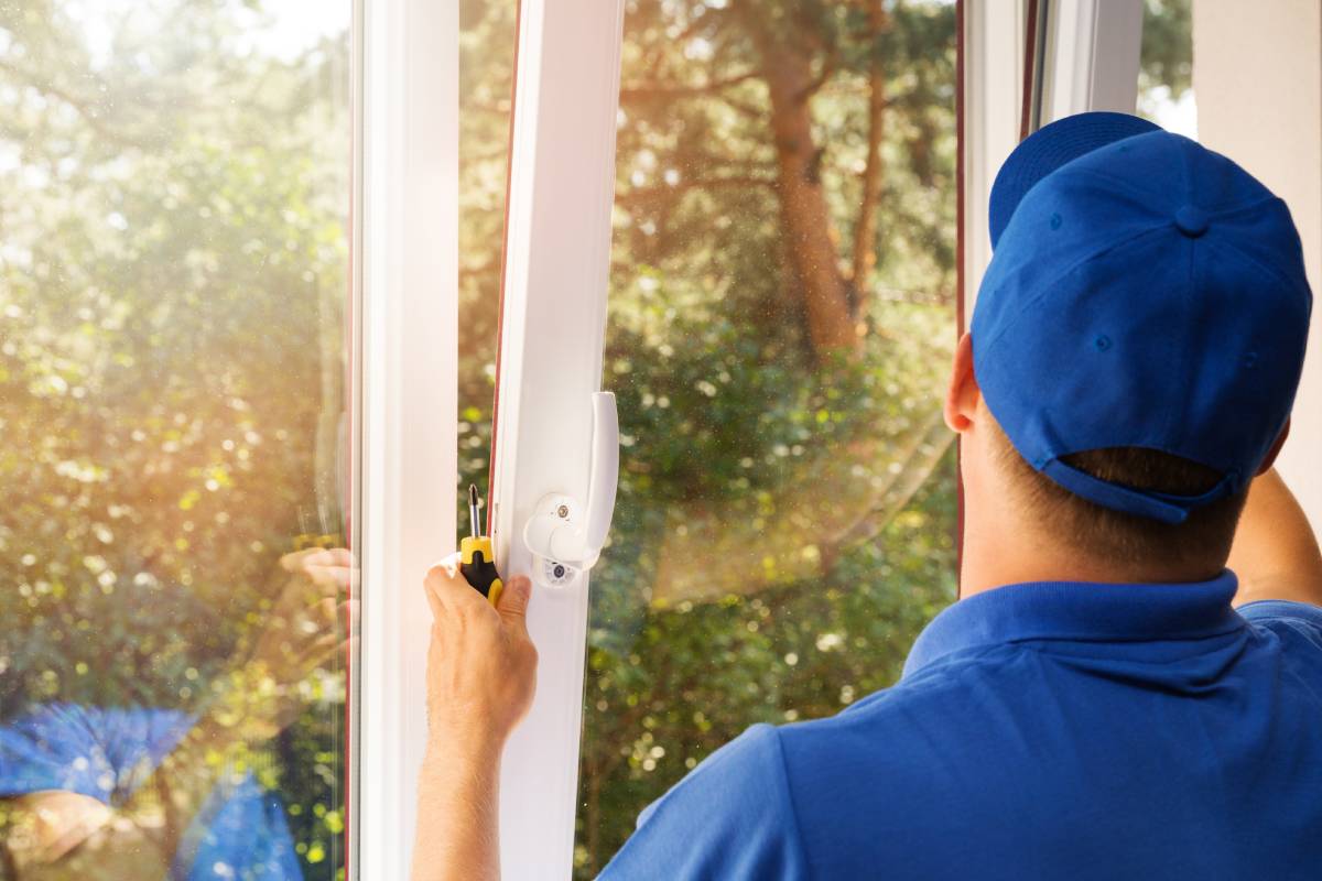 Technician in blue uniform installing a new window in a home near Lexington, KY