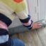 Person wearing a multi-colored placing a draft guard against their front door near Lexington, KY