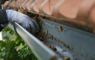 Home’s gutters full of leaves being cleaned out by hand