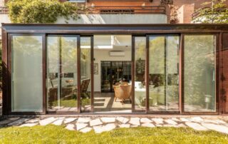 Home with large glass windows and sliding patio doors leading out to a grass yard with a stone path near Lexington, KY