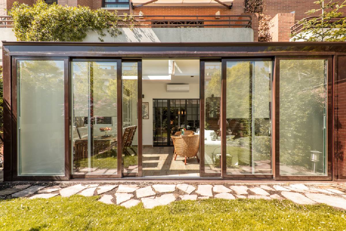 Home with large glass windows and sliding patio doors leading out to a grass yard with a stone path near Lexington, KY