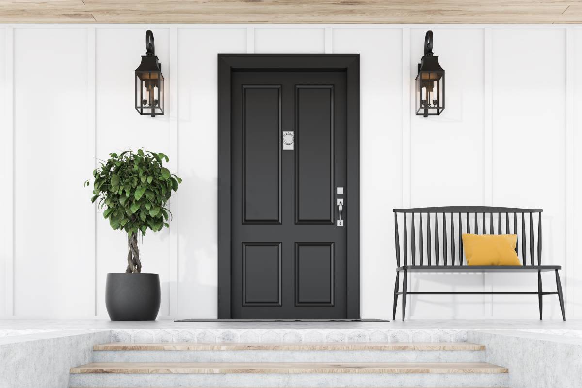 Black entry door against a white exterior with a small tree and bench at Gilkey Windows & Exterior Solutions near Lexington, KY