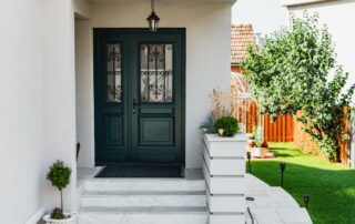 A modern black front door with black hardware and decorative elements on the glass and sidelight at Gilkey Windows & Exterior Solutions near Lexington, KY