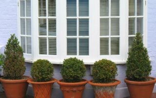 White bow windows on the exterior of a house with precisely manicured shrubs lining the window at Gilkey Windows & Exterior Solutions near Lexington, KY
