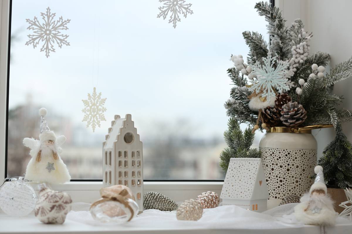 A decorative windowsill with white and neutral-themed holiday decorations featuring pine cones and winter greenery at Gilkey Windows & Exterior Solutions near Lexington, KY