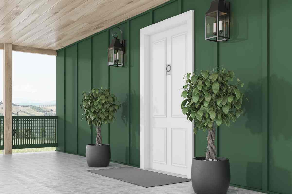 New, white front door on a dark green exterior with modern house lights and potted plants at Gilkey Windows & Exterior Solutions near Lexington, KY