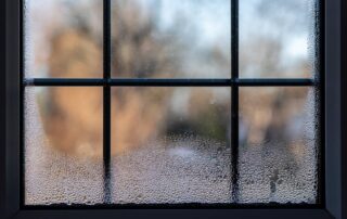 An image focused on window condensation on the glass inside a home during the winter