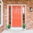 A front door with white trim and bright red that complements the exterior brick