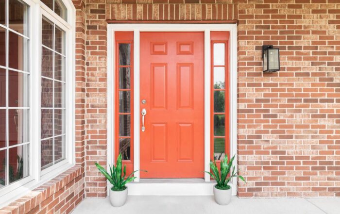 A front door with white trim and bright red that complements the exterior brick