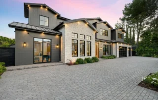 New exterior windows on a beautiful home with outdoor lights on, with a pink sunset